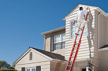 man on ladder painting a house image